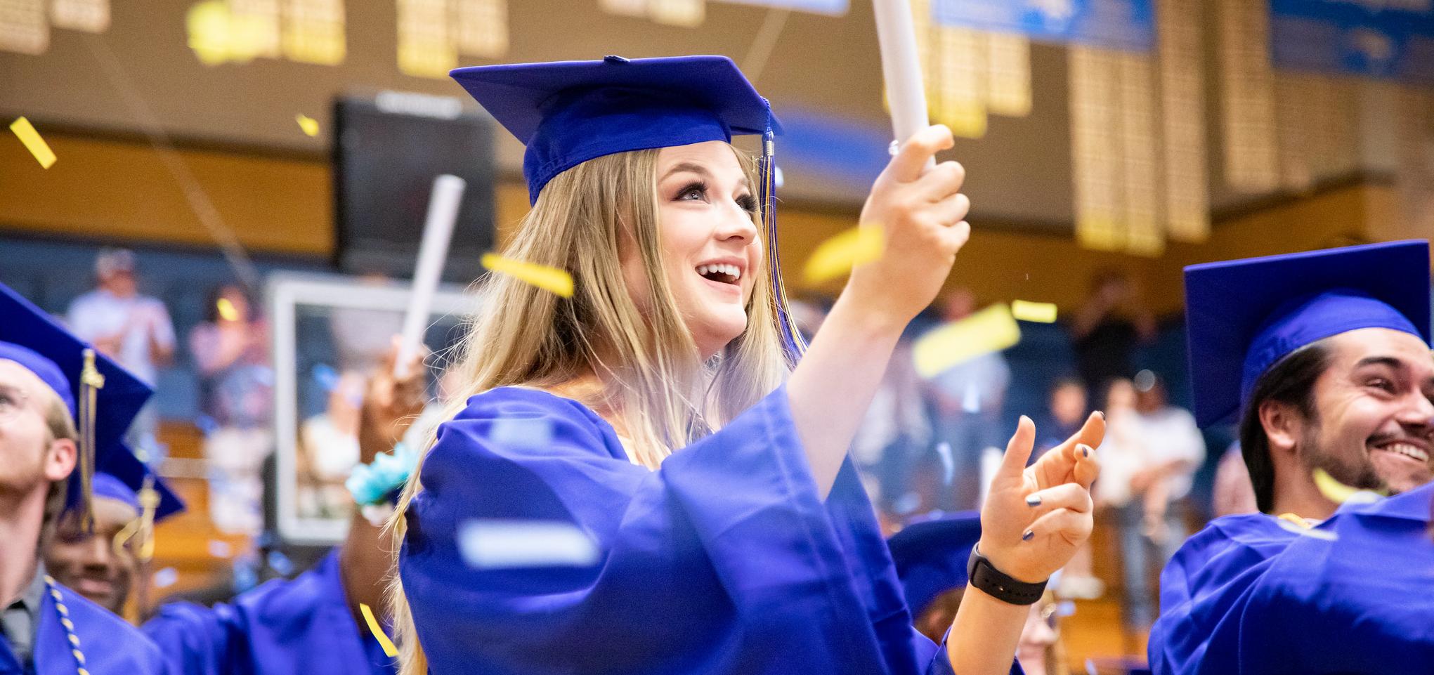 Graduate holds confetti stick at commencement